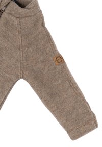 Braune Fleecejacke mit weicher Textur, ausgestattet mit einem Rundhalsausschnitt, einem Frontreißverschluss und einem Leder-Logo-Patch am linken Arm.