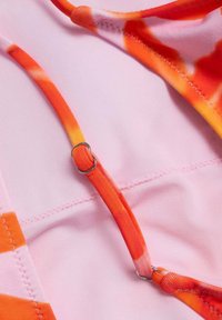 Roze bikini top iz gladkega, raztegljivega blaga, z živahnimi narandžastimi in rdečimi kravato barvami ter srebrnimi pripomočki za varno prilagajanje.