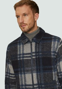 Karo-Jacke aus einer blauen, grauen und schwarzen Wollmischung; mit Reißverschluss vorne, Kragen und strukturiertem Stoff mit breitem Karomuster.