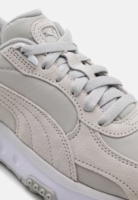 Jasnoszare zamszowe i siateczkowe sneakersy z tonowanymi sznurowadłami, przeszywanym wzorem i białą, wyściełaną podeszwą z podniesionymi okrągłymi wypustkami.