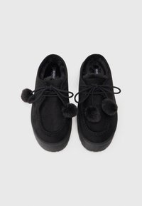 Chaussures en daim noir avec bouts ronds, doublure en fourrure texturée et pompons noirs sur les lacets ; semelles extérieures en caoutchouc et détails cousus.