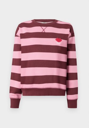 Bordeaux- og rosa-stripete genser med rund hals og ribbestrikkede mansjetter. Har et brodert rødt leppemotiv med teksten "PARIS STUDIO".