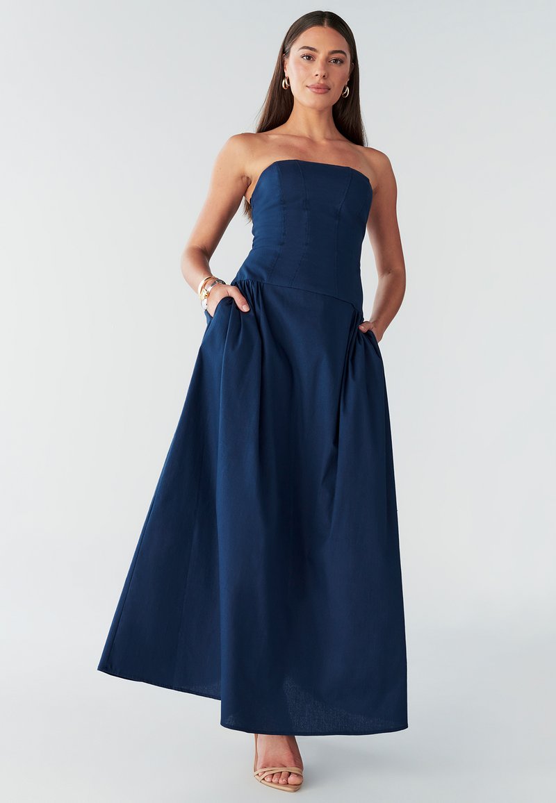 Maxi šaty bez ramienok v námorníckej modrej farbe s priliehavým živôtikom a nazbieranou sukňou, vybavené bočnými vreckami a hladkou, textúrovanou tkaninou.