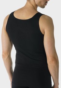 Černý tílko s přiléhavým střihem. Vyrobeno z hladké, elastické tkaniny. Obsahuje kulatý výstřih a široké průramky pro snadný pohyb.