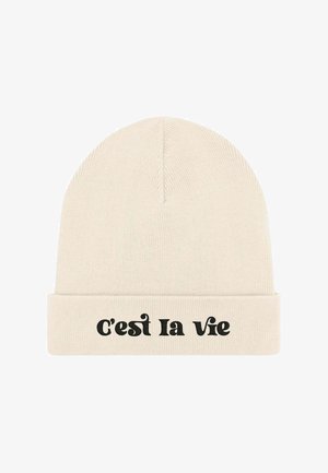 Gorro de punto en color crema suave con puño doblado. Texto negro "C'est la vie" en el frente. Diseño sencillo con textura suave.