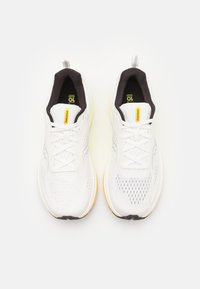 Un paio di scarpe da corsa bianche Saucony con rivestimento interno nero, accenti gialli e lacci, posizionate affianco su uno sfondo bianco.