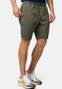 Bermudas vert olive en mélange de coton, avec une taille élastique à cordon de serrage, des poches latérales et une coupe droite.
