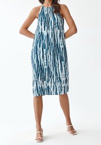 Vestido sin mangas en tonos de azul y blanco con un patrón de tie-dye que presenta rayas verticales. Hecho de una tela suave y fluida; diseño de longitud hasta la rodilla.