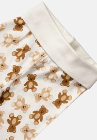 Pigiami per neonati in cotone con una stampa a tutto campo di orsacchiotti color marrone chiaro e scuro su uno sfondo crema, con un morbido polsino bianco.