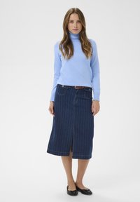 Világoskék garbó, sötét farmer szoknya függőleges csíkokkal, térd alá érő, elöl nyitott, barna övvel és fekete balerinacipővel kiegészítve.