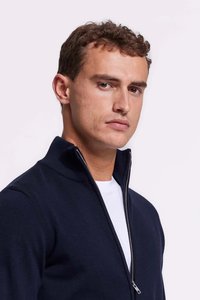 Marineblauwe ritstrui met hoge kraag, gemaakt van een gladde stof. Heeft een zilveren rits en een gelaagd wit T-shirt eronder.