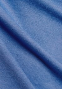 Blue cotton fabric with a fine ribbed texture, folded with gentle curves, showcasing a smooth surface and consistent color throughout.