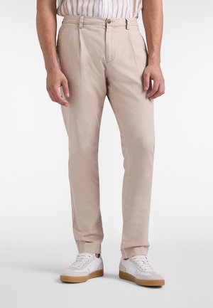 Beige chino's met een rechte pijp, voorzien van een enkele knoopsluiting en onopvallende zijzakken, gecombineerd met witte sneakers.