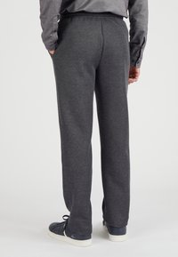 Grijze katoenen joggingbroek met een ontspannen pasvorm, een zachte textuur, zijzakken en een elastische tailleband, gecombineerd met blauwe schoenen.