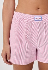 Rood en wit gestreepte shorts met een elastische tailleband. Bevat een logopatch op de taille en heeft een soepele katoenstructuur.