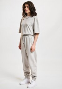 Light gray two-piece outfit consisting of a short-sleeve top and tapered pants, made of soft fabric with an elastic waistband and side pockets.