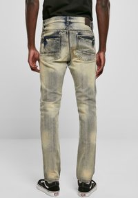 Bleket denimjeans med lett vask, slitt detaljer og slim fit. Har to baklommer og en lærlapp ved livet.