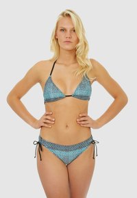 Ensemble de bikini comprenant un haut triangulaire et un bas à nouer sur les côtés, fabriqué en tissu bleu avec un design géométrique et des accents noirs.