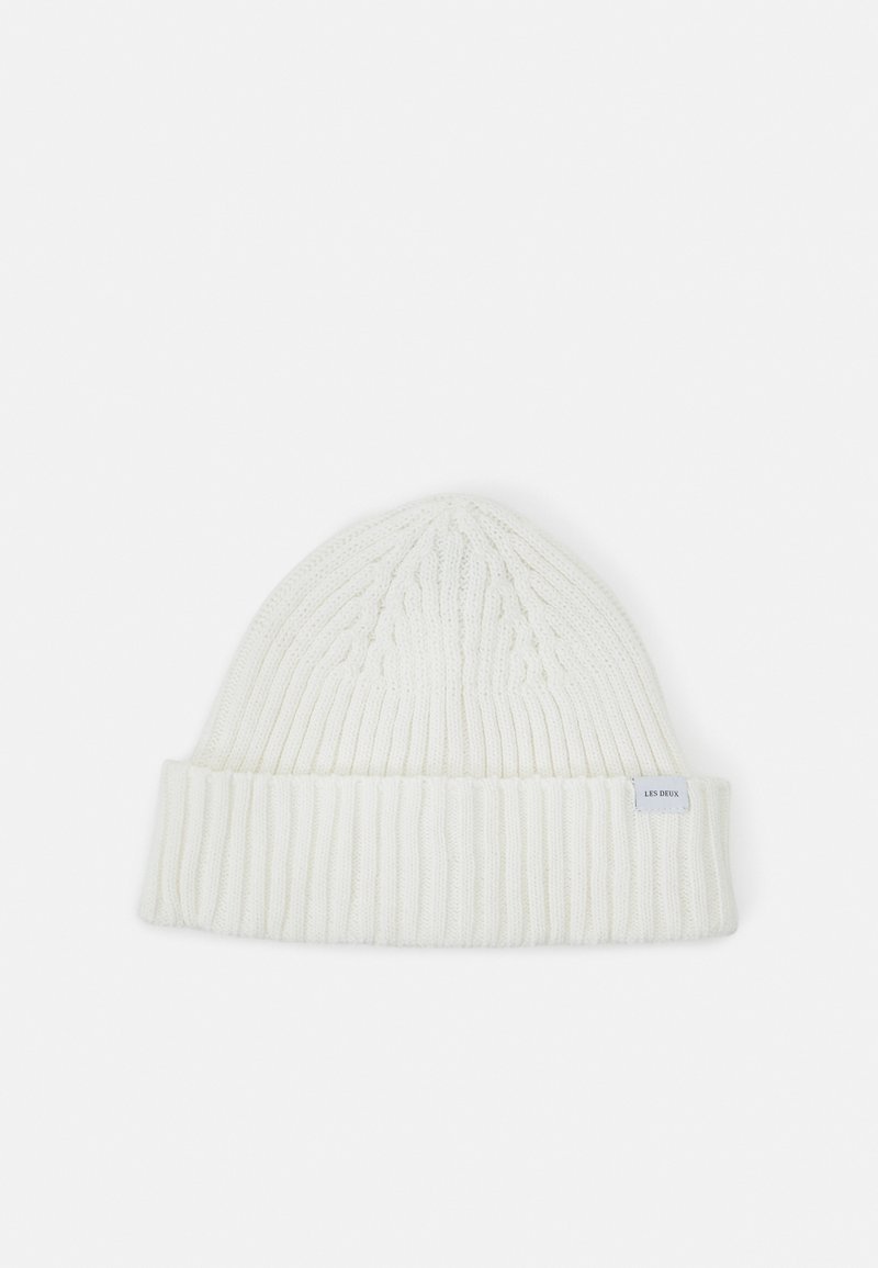 Gorro de malha branco com punho canelado, apresentando um padrão texturizado e um pequeno rótulo de lado. Material macio e quente.