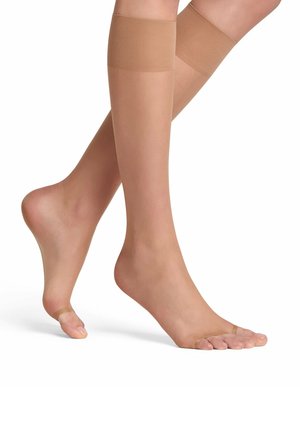 Bas beiges jusqu'aux genoux avec une finition transparente, texture lisse et bande en silicone en haut pour éviter de glisser, laissant entrevoir les orteils.