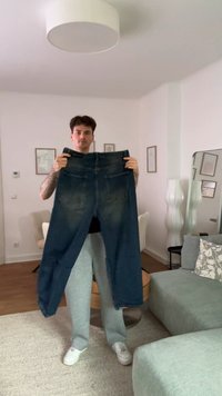 Tamno plave traperice podignute, s ravnim krojem, dva stražnja džepa i izblijedjelim pranjem. Tekstura izgleda čvrsto i izdržljivo.