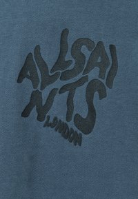 Tejido de algodón azul con un acabado texturizado que presenta un logo negro ondulado que dice "ALLSAINTS LONDON" en una fuente divertida y distorsionada.