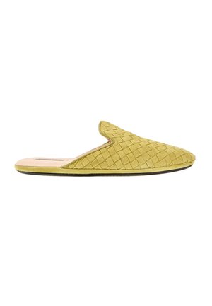Blød gul vævet slip-on mule med flad sål og lukket spids tå på hvid baggrund.