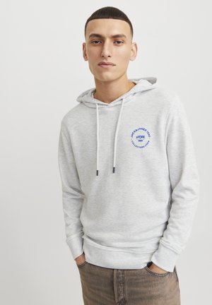 Sudadera gris con cordón, que presenta un logotipo azul circular y texto en el pecho. Tejido suave y puños acanalados; corte holgado.