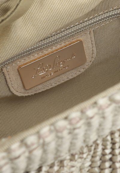 Intérieur d'un sac en tissu beige tissé montrant une étiquette en cuir cousue avec la mention « Liu Jo Legend MADE IN ITALY » sur une plaque en or.