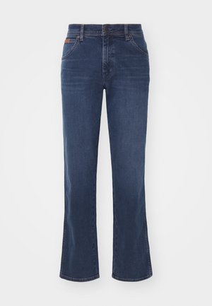 Temno modri, razširjeni kavbojki iz denim materiala s petimi žepi, gumbom za zapiranje in svetlim bledenjem na nogah za teksturo in vizualni interes.