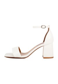 Sandalo con tacco quadrato bianco e cinturino alla caviglia. Realizzato in materiale liscio con un design minimalista e suola marrone.