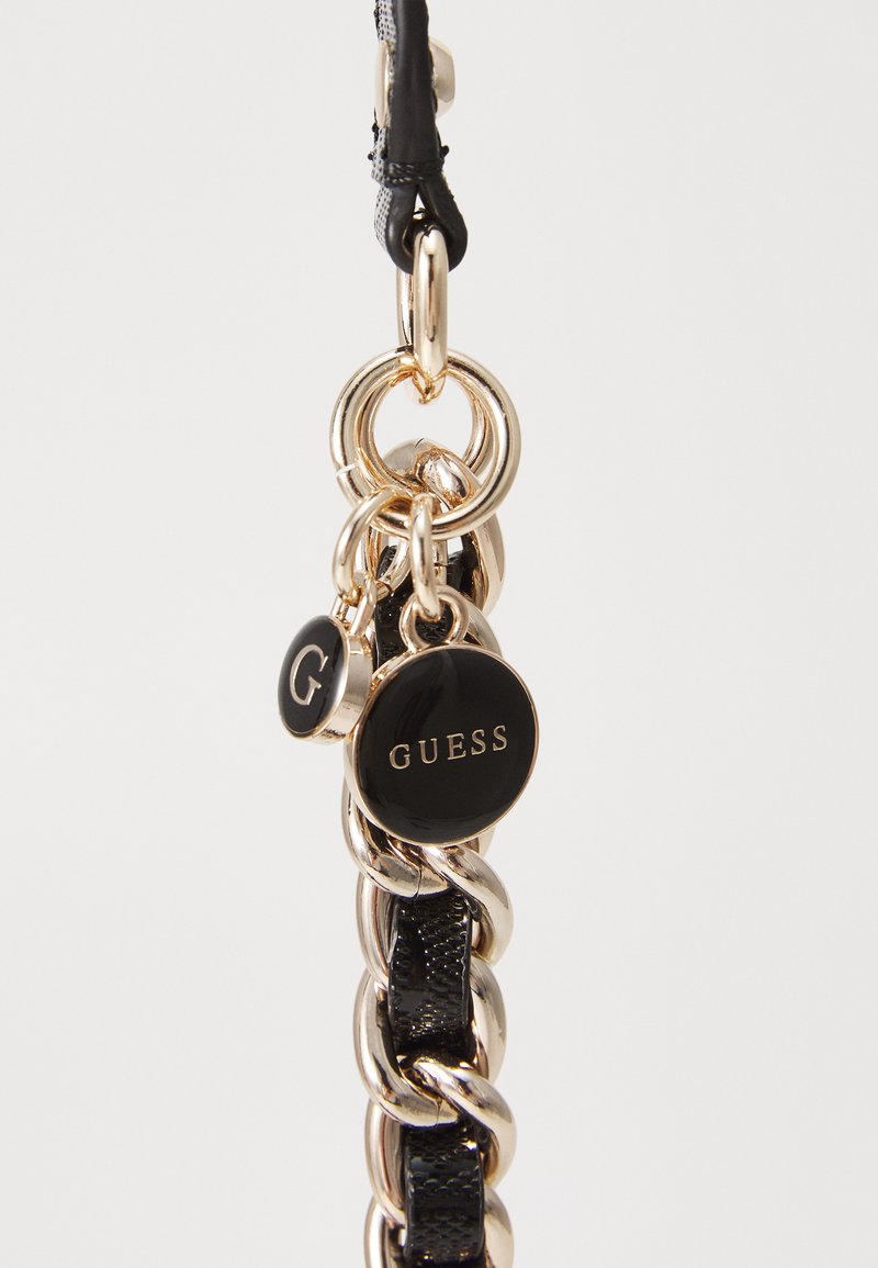 Czarny łańcuszek z metalowymi złotymi ogniwami, z dwoma zawieszkami: jedna okrągła czarna z napisem "GUESS" w złotym kolorze oraz mniejsza okrągła zawieszka z "G.".