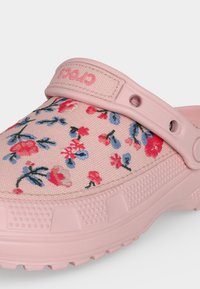 Ροζ Crocs clog με ανώτερη ύφανση με λουλουδάτο σχέδιο, ροζ ρυθμιζόμενο λουράκι στη φτέρνα και υφή στη σόλα για κράτημα και άνεση.