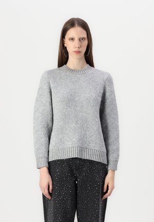 Gray knitted sweater with a textured pattern, round neckline, and ribbed cuffs and hem; paired with dark jeans featuring dot patterns.