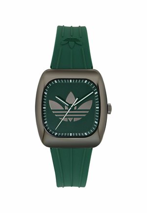Kvadratni temno zeleni številčnica ure z logotipom Adidas trefoil, zelenima kazalcema za ure in minute, belim sekundnim kazalcem ter usklajenim zelenim gumijastim paščkom.