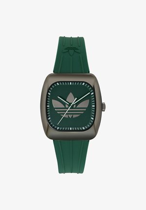 Négyzet alakú sötétzöld óralap Adidas háromlevelű logóval, zöld óra- és percmutatóval, fehér másodpercmutatóval, valamint hozzáillő zöld gumiszíjjal.