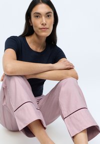 Mörkblå ribbad t-shirt kombinerad med ljusrosa vida byxor med dekorativt mörkrosa sömnad vid nederdelen.