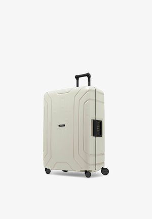 Valigia rigida bianca con quattro ruote, manico telescopico e serratura a combinazione laterale, in piedi su sfondo bianco.