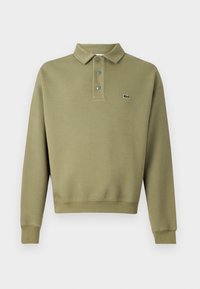 Sudadera verde oliva con cuello tipo polo, tapeta de tres botones y puños acanalados. Presenta un pequeño logotipo en el lado izquierdo.