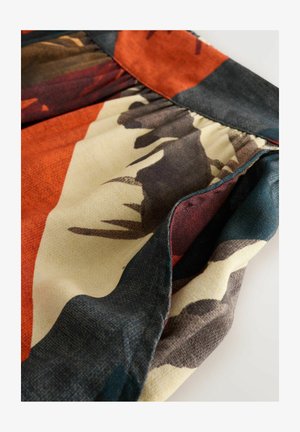 Bunter Stoff mit abstrakten Mustern in erdigen Tönen von Orange, Braun und Teal. Strukturiert mit gerafften Abschnitten und kontrastierenden Nähten.