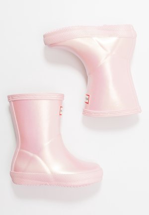 Różowe, błyszczące dziecięce kalosze z teksturowaną podeszwą oraz czerwono-białymi etykietami z logo z przodu, pokazane z boku i od spodu.