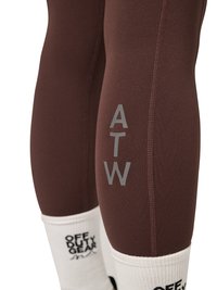 Ben iført brune atletiske leggings med "ATW" tekst på læggen og hvide sokker med sort "OFF DUTY GEAR" tekst.