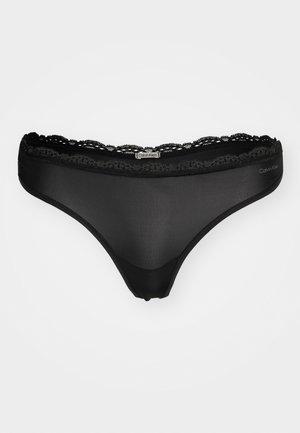 String noir en lingerie fabriqué en tissu transparent avec des finitions en dentelle délicate, doté d'une taille élastiquée et d'un accent logo sur le côté.
