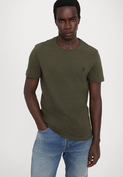 Olivgrön t-shirt med kort ärm i en strukturerad tygkvalitet och rundad halsringning, tillsammans med ljusblå jeans i denim med en liten logotypdetalj.