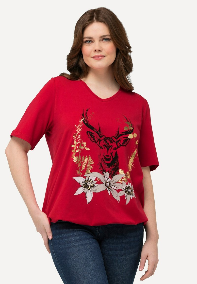 Camiseta corta roja de manga corta con un gráfico de ciervo negro rodeado de diseños florales en tonos blanco y dorado. Escote en forma de V y corte holgado.