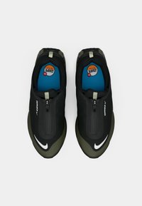 Juodi ir tamsiai žali sportbačiai su lygaus audinio viršumi, užtrauktuko detalėmis, mėlynomis vidpadžiais ir balta "Nike" logotipu. Suapvalinta nosies forma.