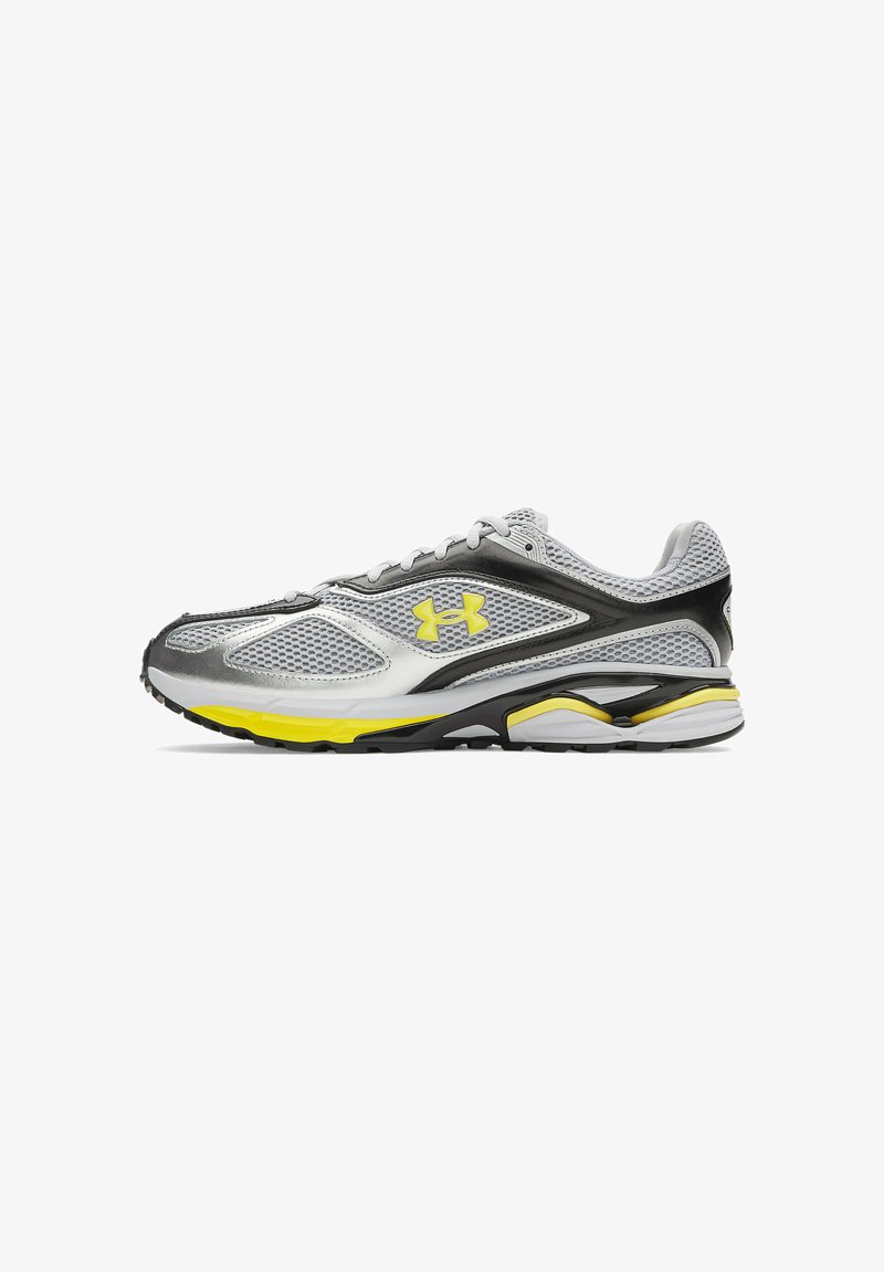 Scarpa sportiva con tomaia in rete grigia, dettagli in nero e argento, suola intermedia gialla e un profilo elegante. Design leggero con lacci.