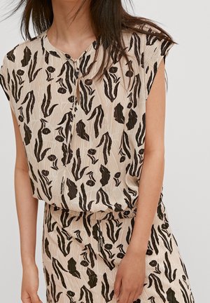 Helles beiges Oberteil aus strukturiertem Stoff mit einem auffälligen schwarzen und grünen abstrakten Muster. Kurze Ärmel und runder Ausschnitt.