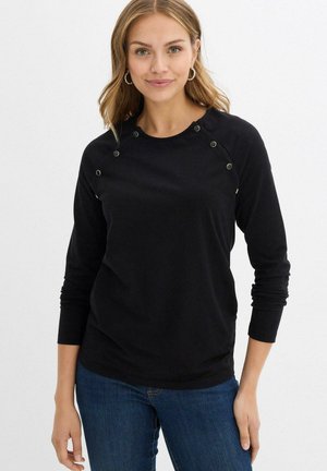 Top nero a maniche lunghe realizzato in tessuto morbido, con dettagli di bottoni a pressione sulle spalle e polsini aderenti. Abbinate a jeans blu.