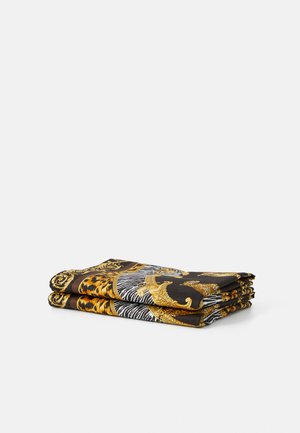 Folded silk scarf featuring a bold animal print in shades of black, gold, and yellow, with intricate detailing and ornate borders.